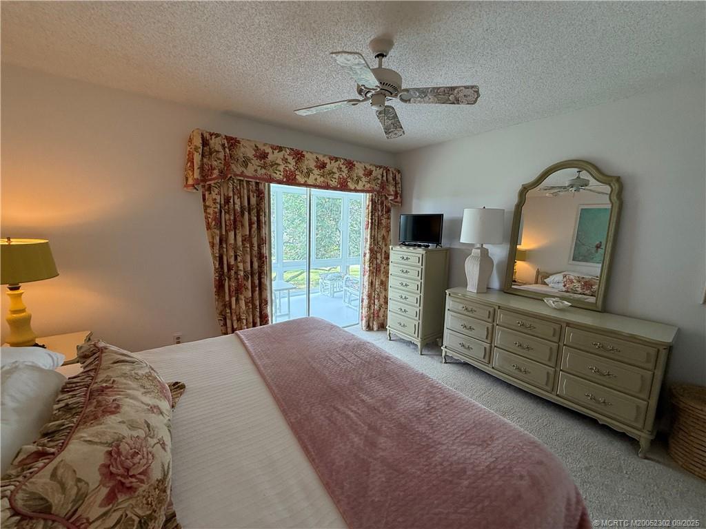 2929 Southeast Ocean Boulevard, Unit 8 Stuart, FL 34996 - Photo 16 of 22 a bedroom with a bed a mirror on dresser and a large window