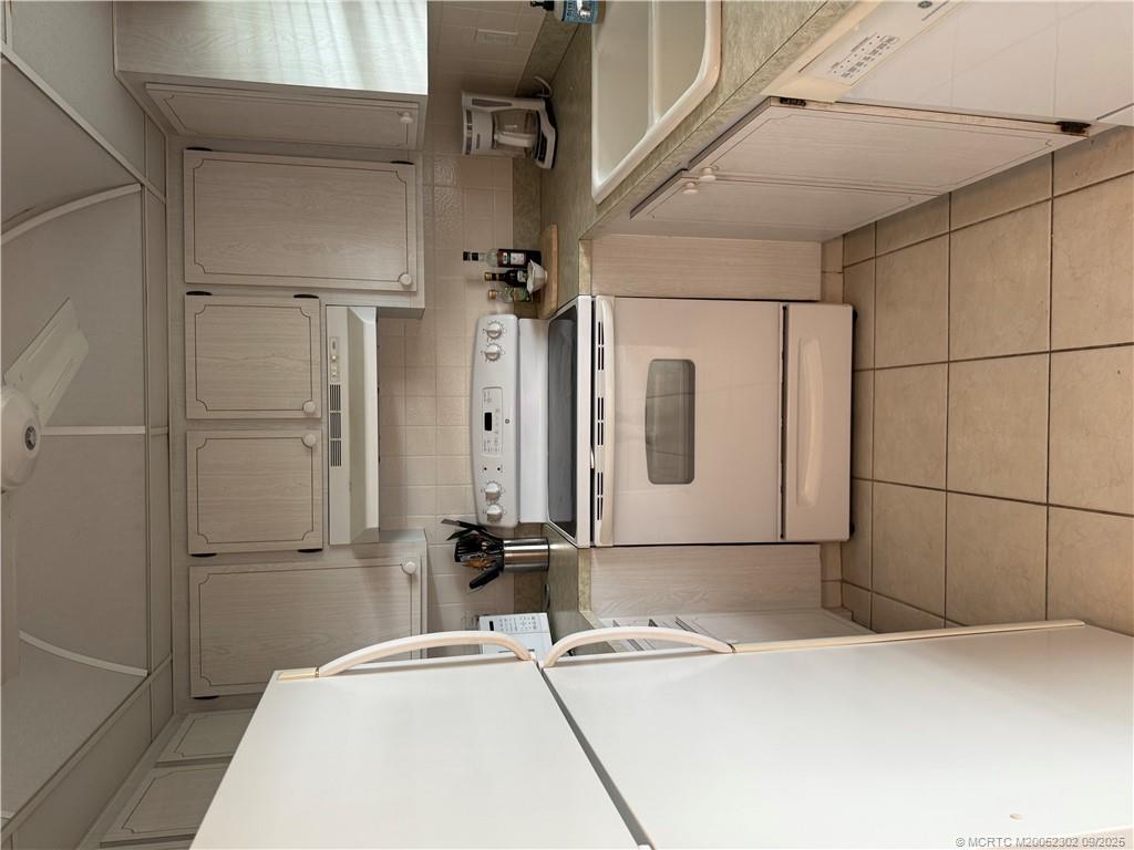 2929 Southeast Ocean Boulevard, Unit 8 Stuart, FL 34996 - Photo 7 of 22 a kitchen with a stove top oven a sink and white cabinets