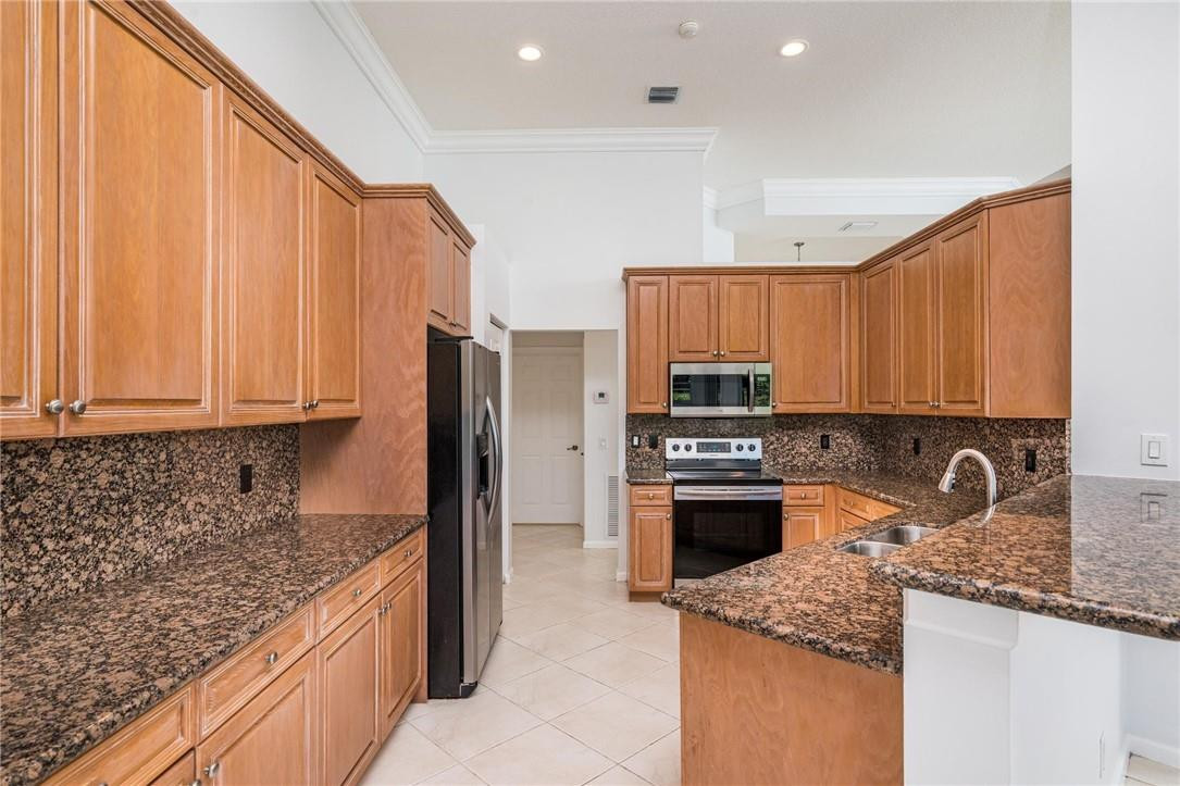 3759 Oak Ridge Circle Weston, FL 33331 - Photo 17 of 31 a kitchen with stainless steel appliances granite countertop a stove a sink dishwasher and a refrigerator with wooden cabinets