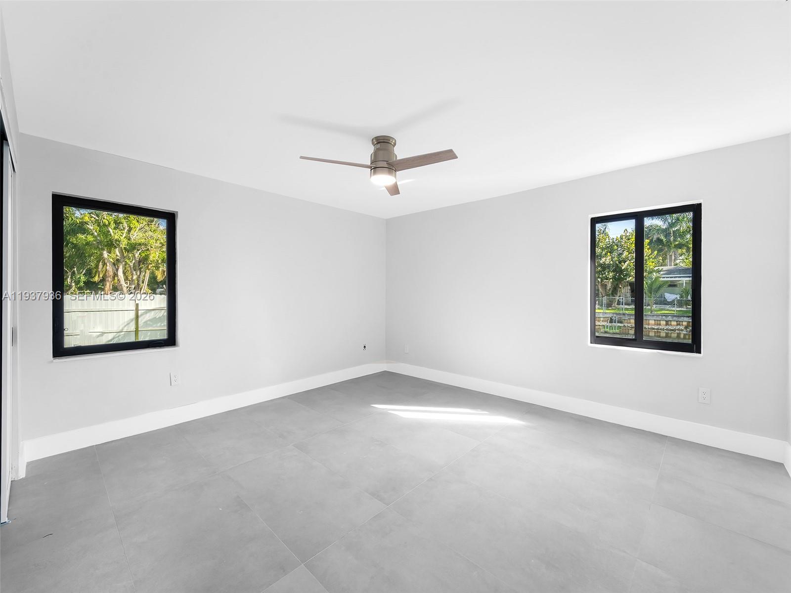 212 Southwest 7th Street Hallandale Beach, FL 33009 - Photo 12 of 23 an empty room with ceiling fan and windows
