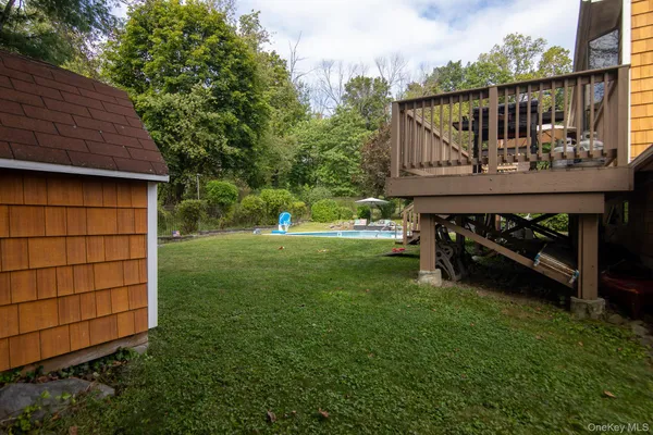 a view of a backyard with large trees and a small barn