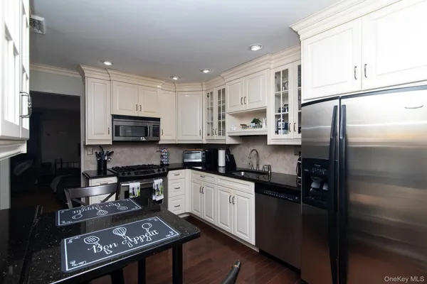 a kitchen with stainless steel appliances granite countertop a refrigerator a sink a stove a microwave and wooden cabinets