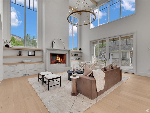 13216 Telemark Lane Draper, UT 84020 - Photo 8 of 41 Living room featuring light wood finished floors, a warm lit fireplace, and suspended lighting