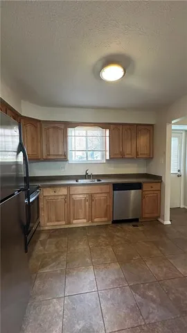 a large kitchen with granite countertop a stove a sink a microwave and a refrigerator