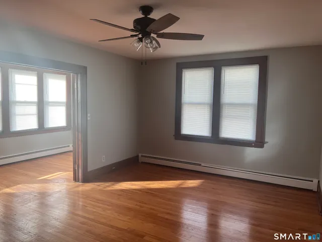 a view of an empty room with wooden floor and a window