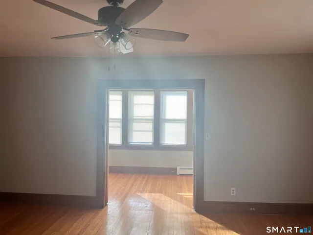 a view of an empty room with wooden floor and a window