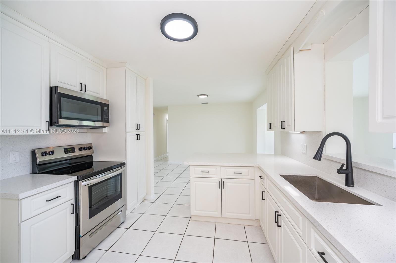 532 Northwest 15th Street Homestead, FL 33030 - Photo 16 of 32 a kitchen with a sink a stove and cabinets