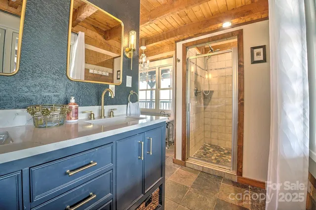 a bathroom with a granite countertop sink a mirror and shower