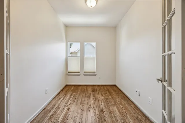 an empty room with wooden floor and windows