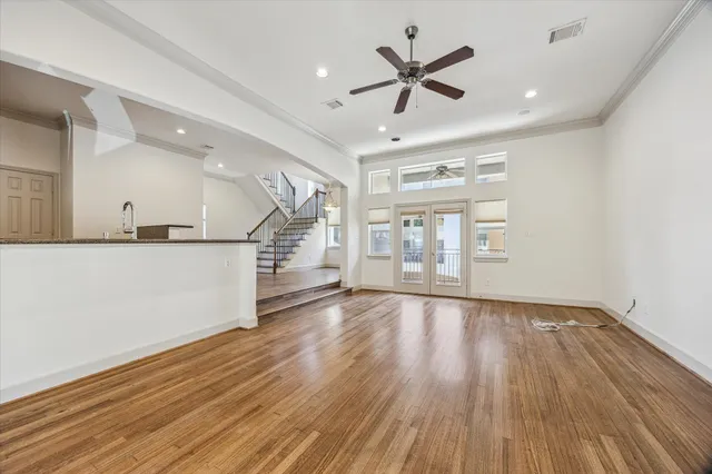 a view of a livingroom with wooden floor a ceiling fan and windows