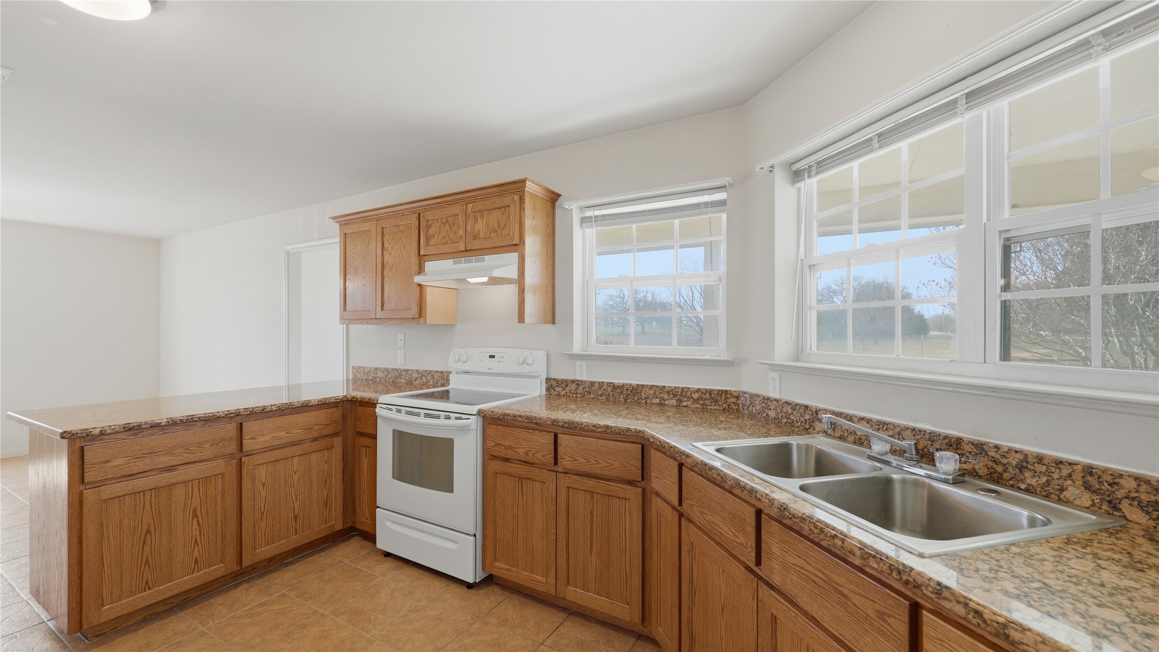 369 Young School House Road Smithville, TX 78957 - Photo 7 of 30 Kitchen featuring white range with electric stovetop, a peninsula, wood finish cabinetry, and light tile patterned floors