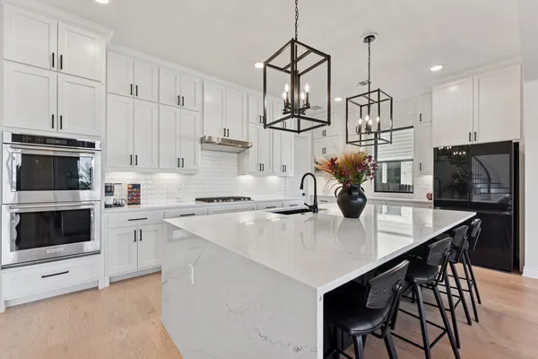 a kitchen with kitchen island a stove a microwave a sink a center island and chairs