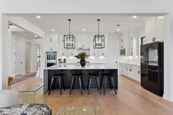 a kitchen with stainless steel appliances kitchen island granite countertop a dining table chairs and a refrigerator