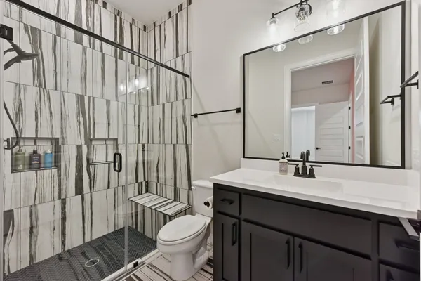 a bathroom with a sink a toilet a mirror and shower