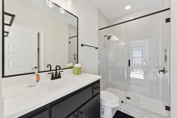 a bathroom with a sink a toilet a mirror and shower