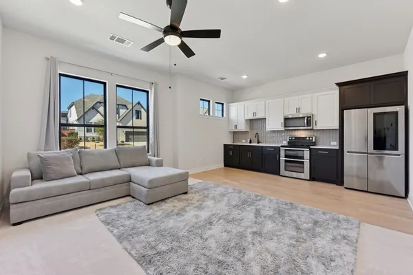 a living room with stainless steel appliances furniture and a kitchen