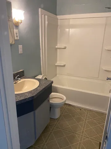 a bathroom with a granite countertop sink toilet and shower