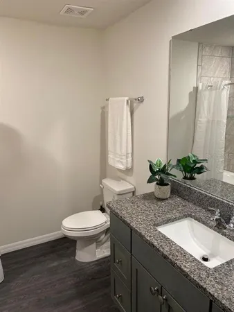 a bathroom with a granite countertop sink a toilet and mirror