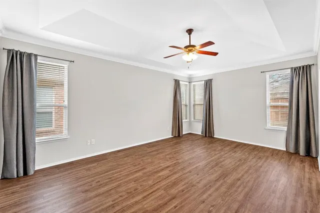 a view of empty room with wooden floor and fan