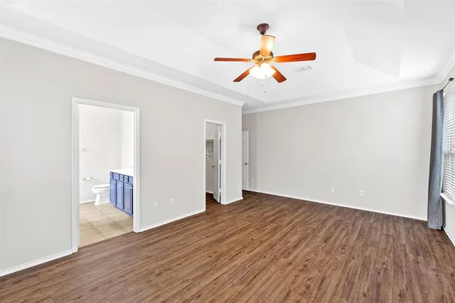 a view of an empty room with wooden floor and a ceiling fan
