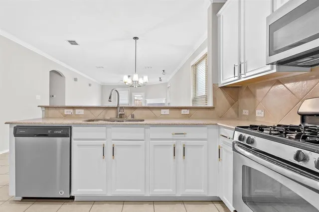 a kitchen with granite countertop a stove and white cabinets