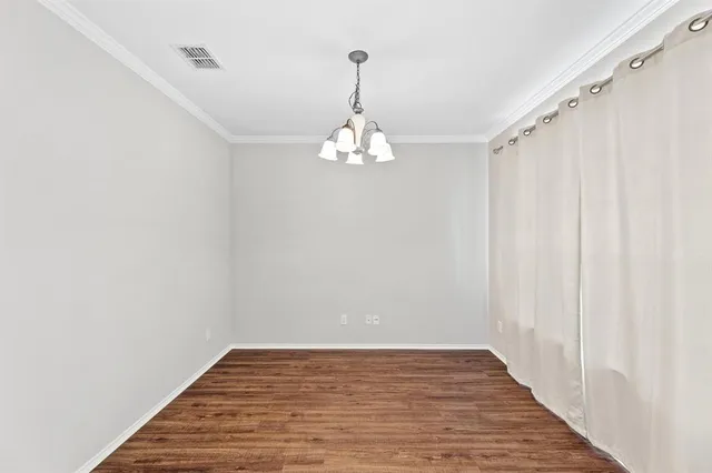 a view of a hallway with wooden floor and a chandelier