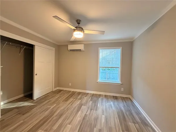 an empty room with wooden floor fan and windows