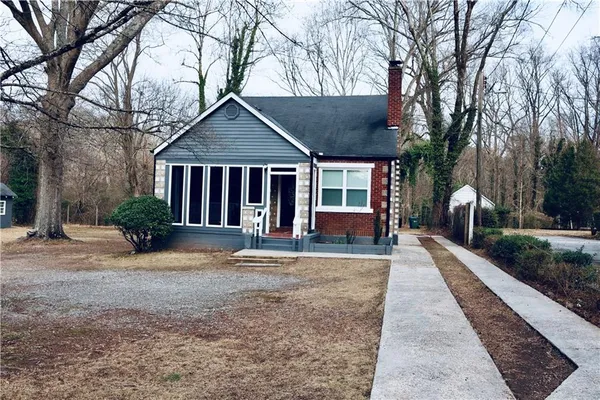 a view of a house with a yard and large tree