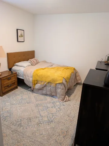a bedroom with a bed and a lamp on desk