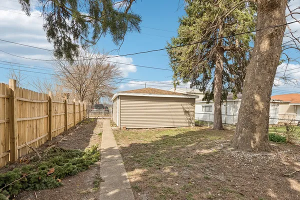 a view of a yard with wooden fence and a large tree