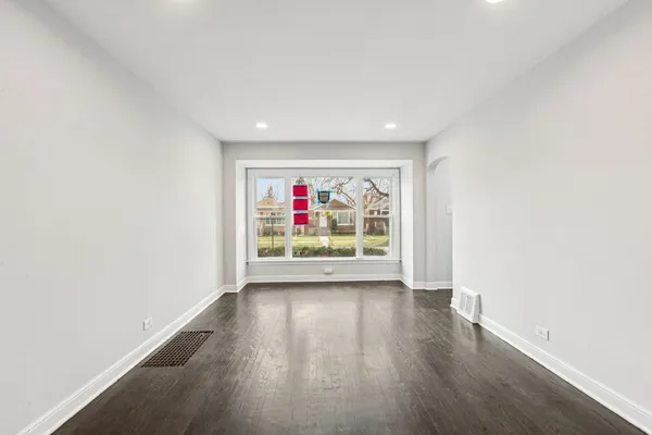 a view of an empty room with wooden floor and window