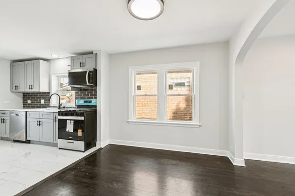 a kitchen with granite countertop a stove top oven a sink dishwasher and a microwave oven on the wooden floor