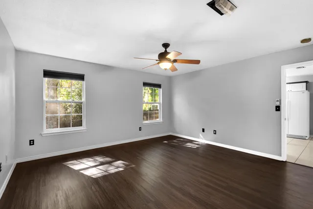 an empty room with windows and ceiling fan