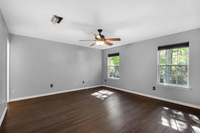a view of empty room with wooden floor and fan