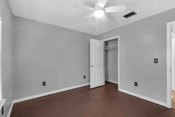 an empty room with a ceiling fan and a window