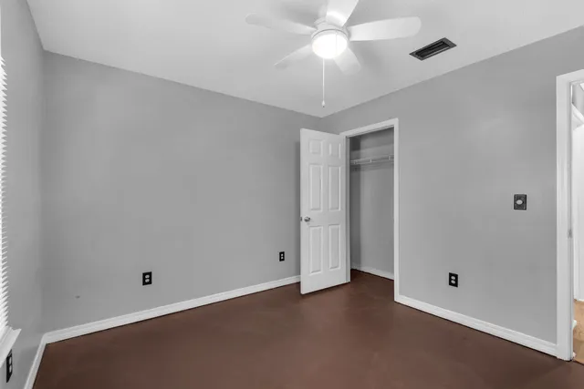 an empty room with a ceiling fan and a window