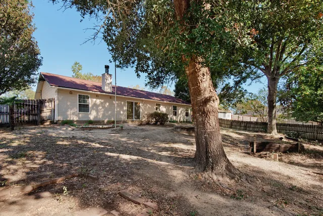 a front view of a house with yard tree and outdoor seating