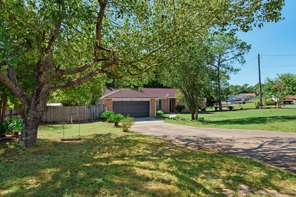 a small yard with large trees and wooden fence