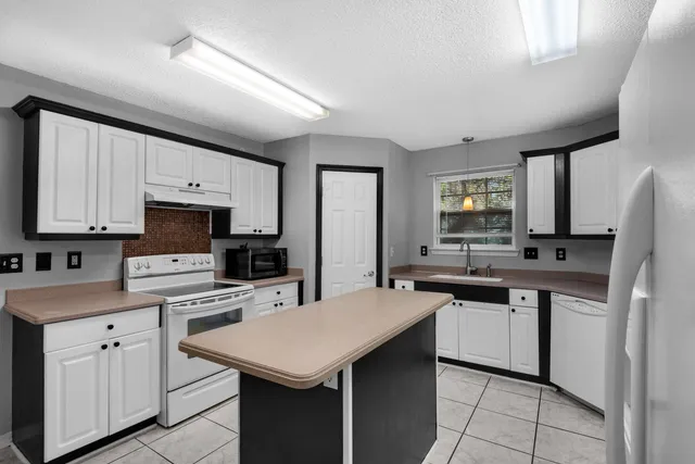 a kitchen with a sink a stove a refrigerator and white cabinets