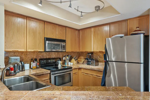 a kitchen with stainless steel appliances granite countertop a refrigerator a sink dishwasher a stove with wooden cabinets and floor