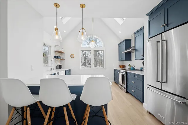 a open kitchen with stainless steel appliances granite countertop a stove a refrigerator a kitchen island a dining table and chairs with wooden floor