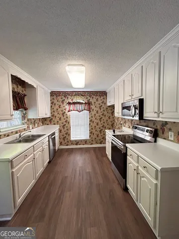 a kitchen with stainless steel appliances a stove top oven a sink a counter space and cabinets