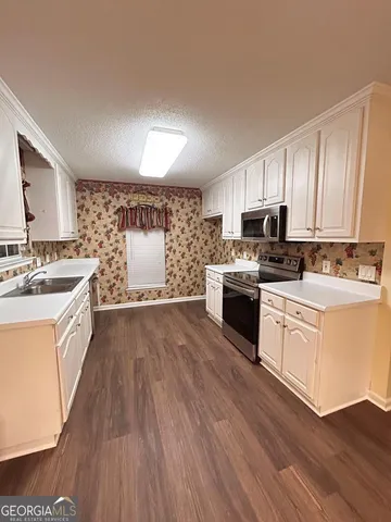 a kitchen with stainless steel appliances a white stove top oven sink and cabinets