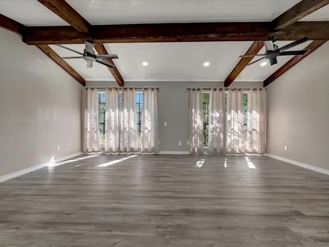 a view of an empty room with wooden floor and windows