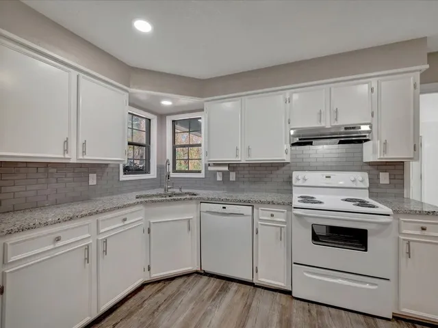 a kitchen with granite countertop white cabinets and white appliances
