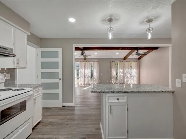a kitchen with stainless steel appliances granite countertop a sink and cabinets with wooden floor