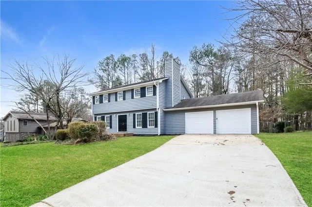 a front view of a house with a garden and trees