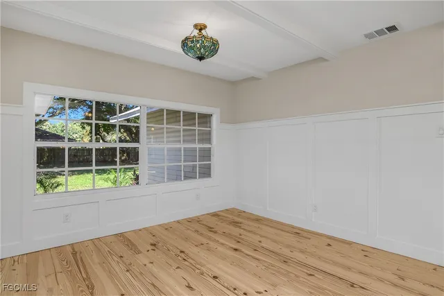 a view of an empty room with a window and hardwood floor