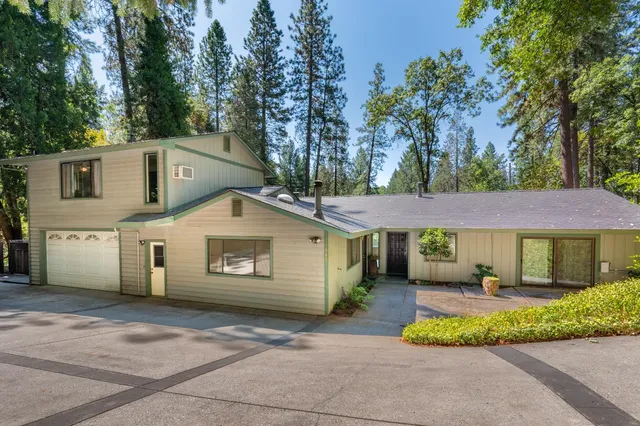 a front view of a house with a garden and trees