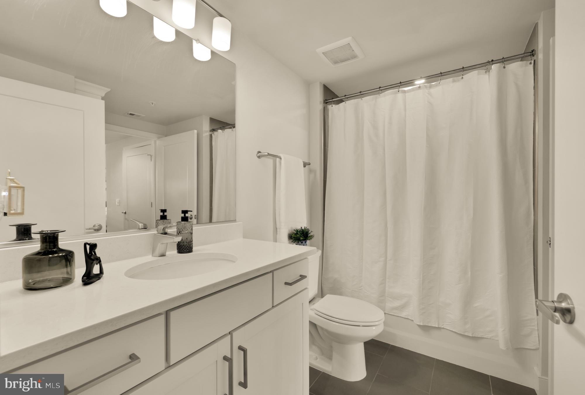 50 Florida Avenue Northeast, Unit 412 Washington, DC 20002 - Photo 12 of 29 a bathroom with a sink a toilet a mirror and shower curtain